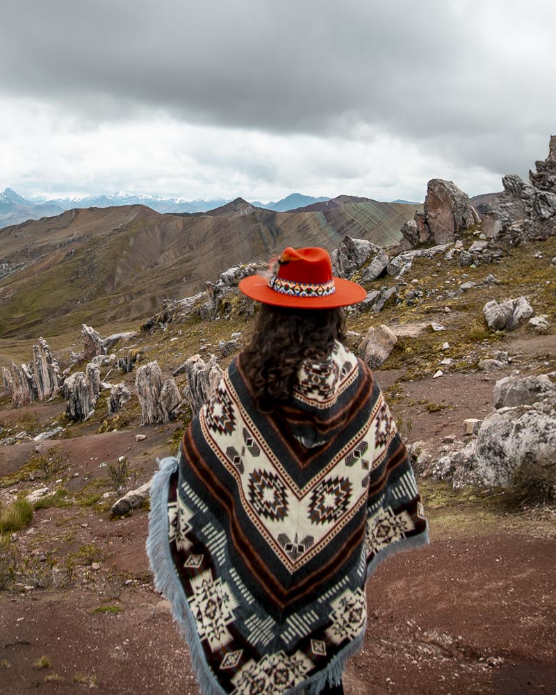 Turista com roupa andina na montanha colorida de Palccoyo