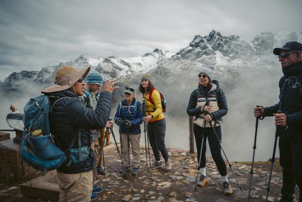 Grupo de turistas com bastões de trekking e seu guia se preparando para iniciar a caminhada até a Montanha das Cores de Vinicunca