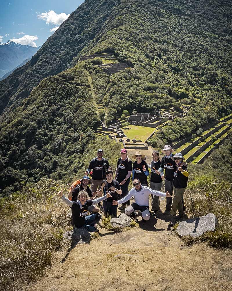 Turistas posando com o sítio arqueológico de Choquequirao ao fundo