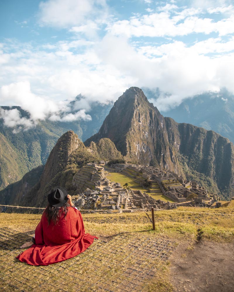 Turista com poncho andino vermelho na cidadela de Machu Picchu
