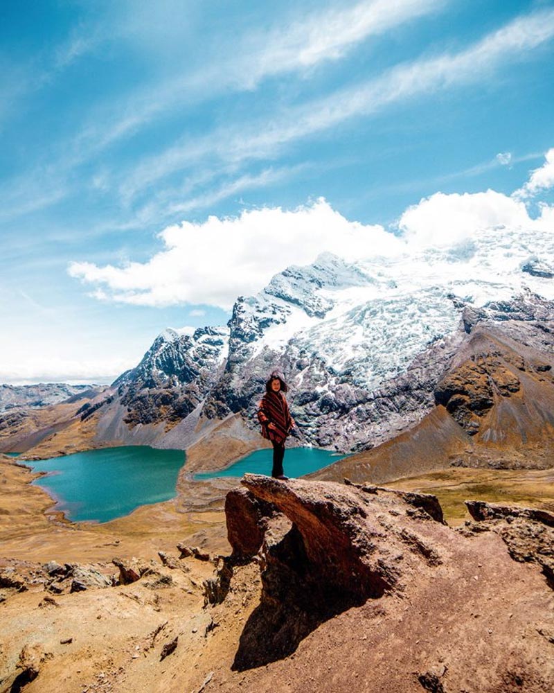 Turista com poncho andino e a montanha Ausangate como pano de fundo