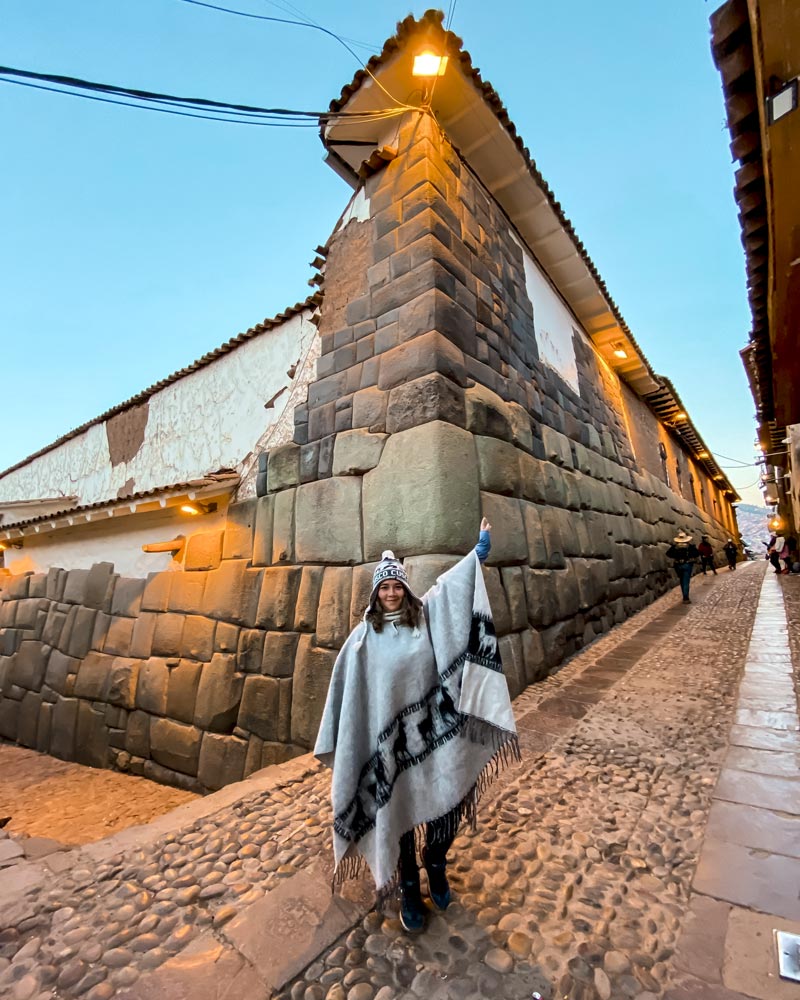 Turista com poncho andino na pedra de 12 ângulos