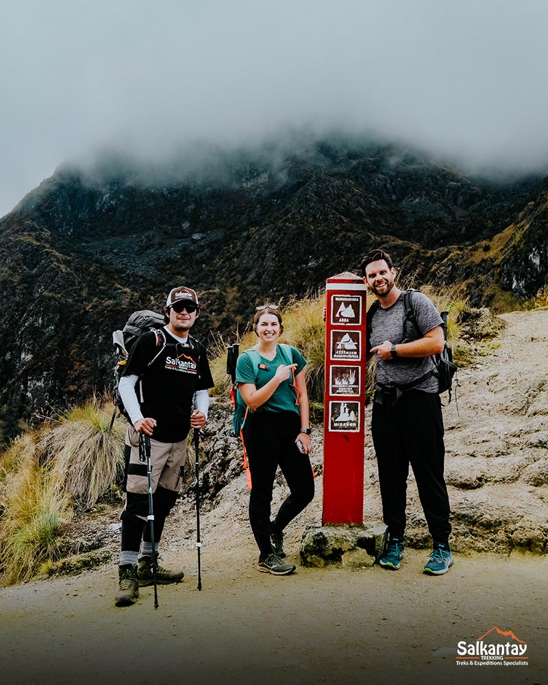 Um guia e dois turistas na Passagem da Mulher Morta, na rota da Trilha Inca