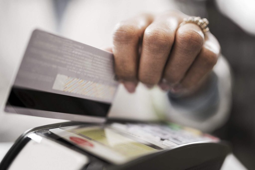 Pessoa usando POS com seu cartão de crédito