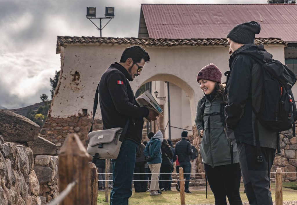 Casal de turistas com seu guia visitando o complexo arqueológico de Chinchero