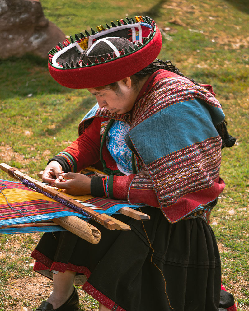 Mulher tecendo em Chinchero com seu traje tradicional e o famoso tear de cintura
