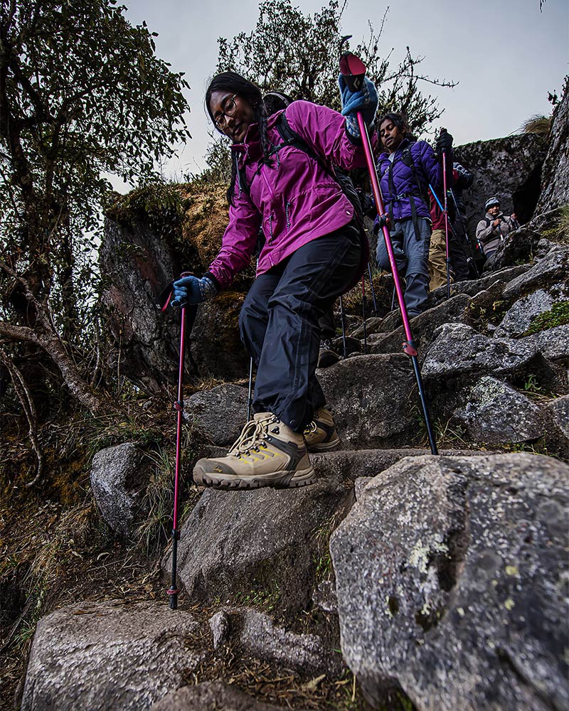 Turistas descendo as escadarias incas em Machu Picchu com bastões de trekking