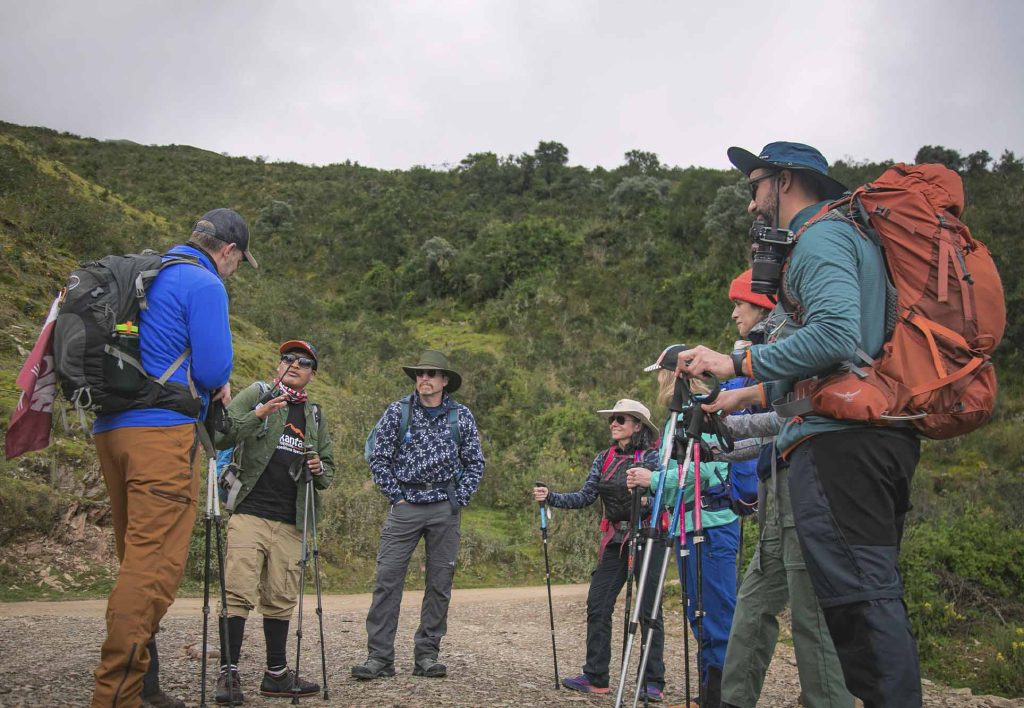 Grupo de turistas na trilha Salkantay, com mochilas, gorros e bastões de trekking