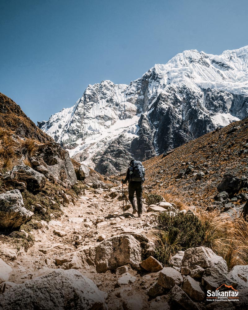 Turistas a caminhar em direção à passagem de Salkantay, ao lado da imensa montanha Salkantay.