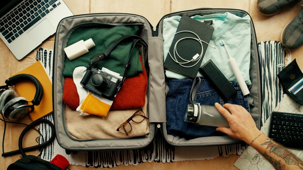 Um viajante que organiza e guarda cuidadosamente suas roupas e equipamentos em uma mochila de trilha.