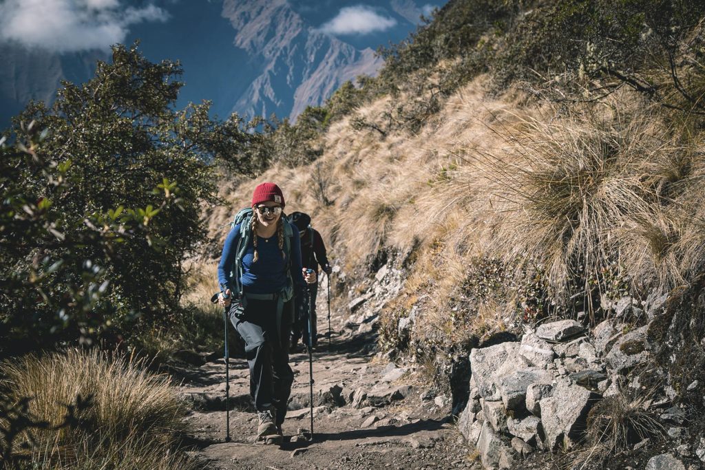Mulher caminhando com bastões de caminhada pela Trilha Inca em direção a Machu Picchu.