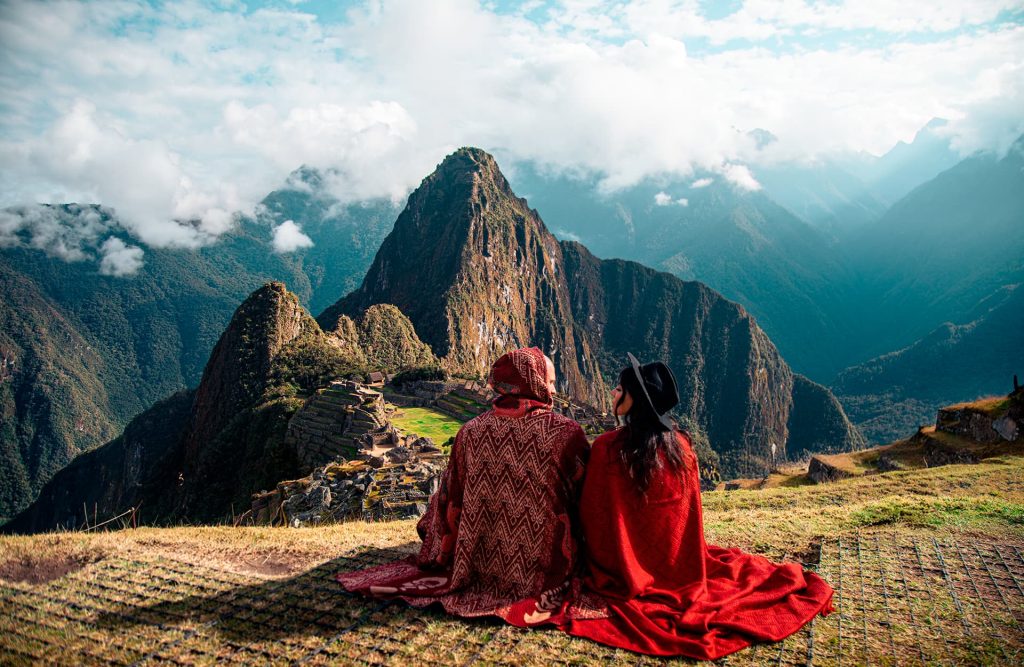 Um turista em pé, contemplando a cidadela de Machu Picchu do alto.