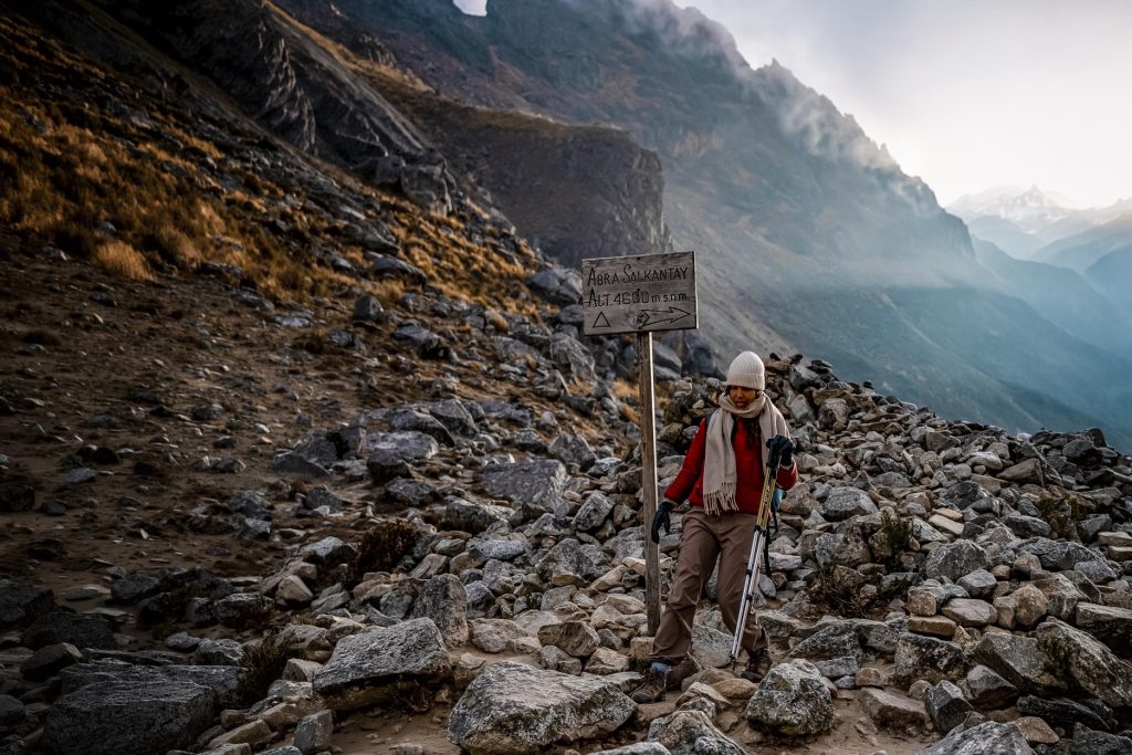 Turista solitário ao lado de uma placa no Passo de Salkantay.