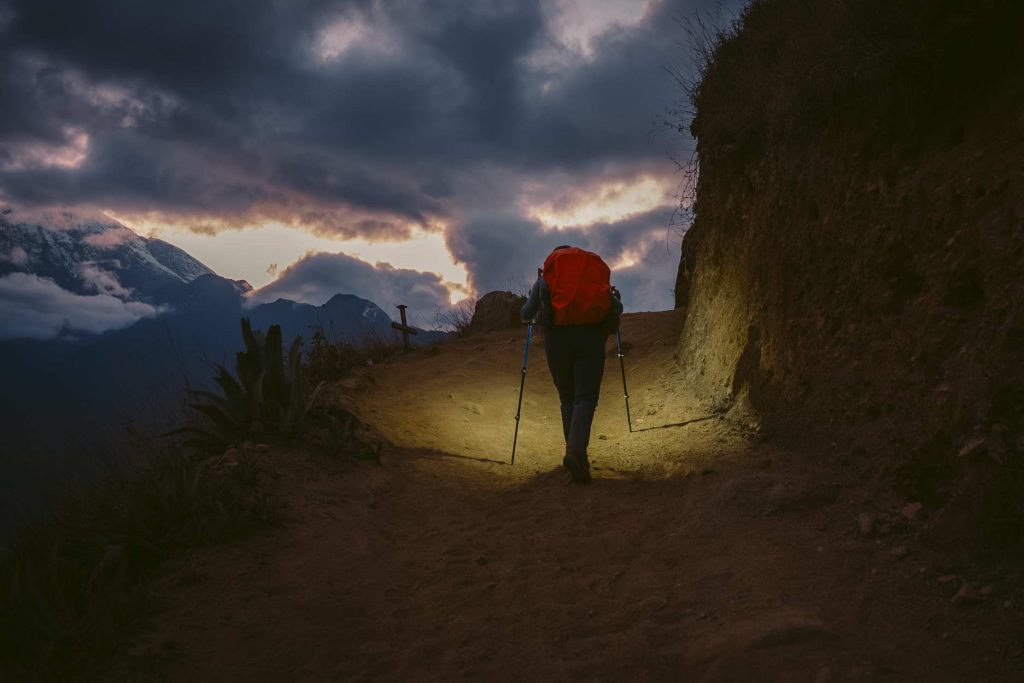 Turista caminhando com lanterna ao entardecer na trilha para Choquequirao