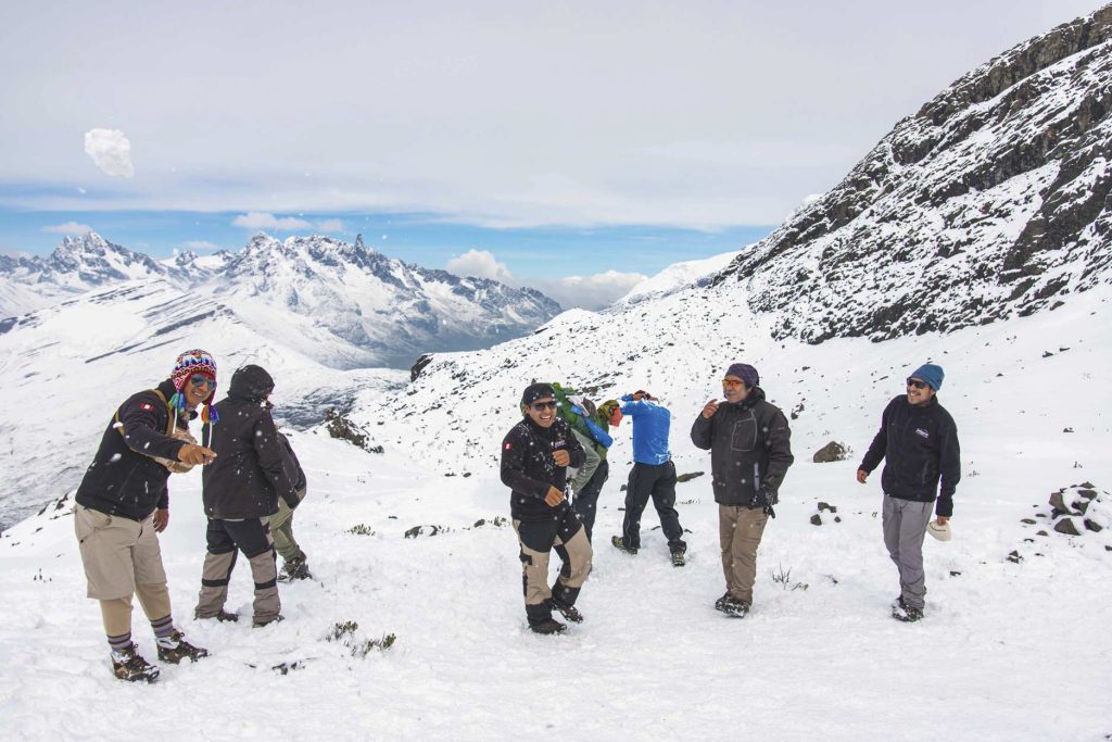 Turistas e guias de trekking desfrutam da trilha Ausangate em meio à neve.