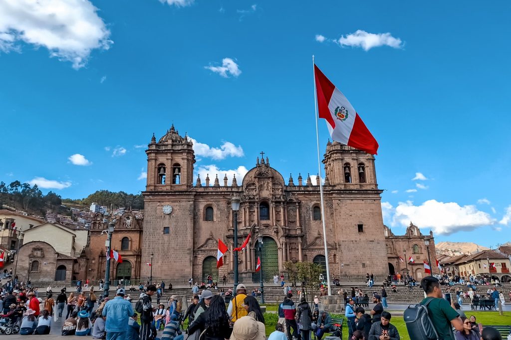 A praça principal de Cusco estava repleta de pessoas agitando uma bandeira peruana.